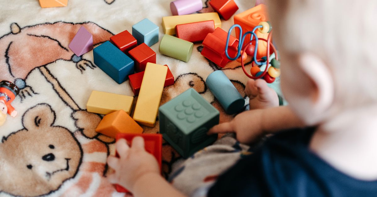 Bebê brincando alegremente com blocos de montar coloridos sobre um cobertor
