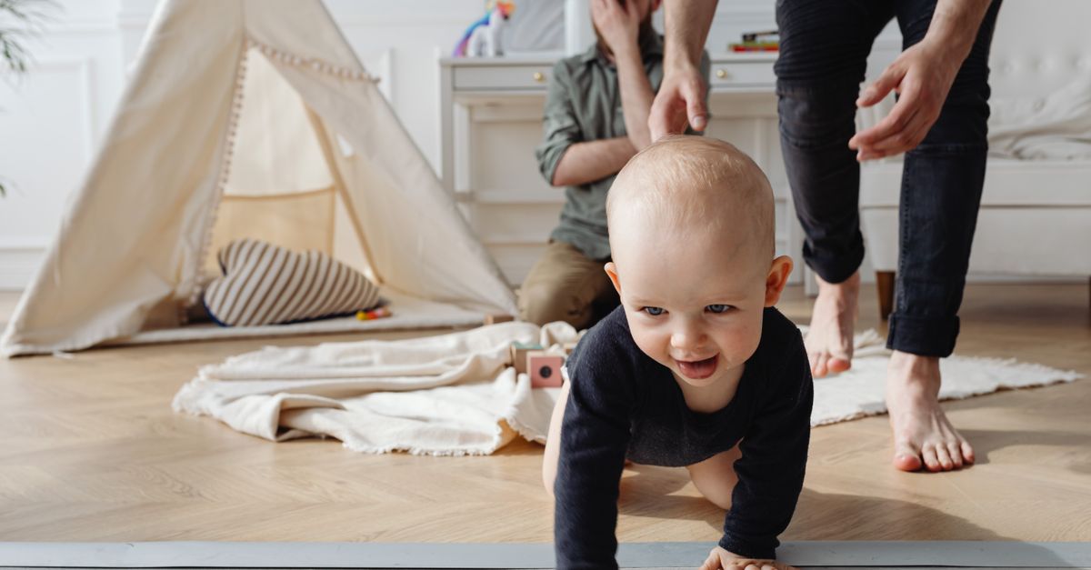 Bebê sorridente engatinhando no chão, cercado de brinquedos