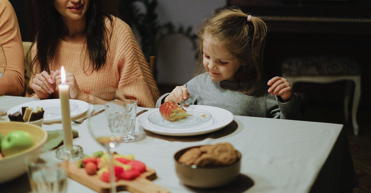 Menina sentada à mesa de jantar em casa, comendo tranquilamente