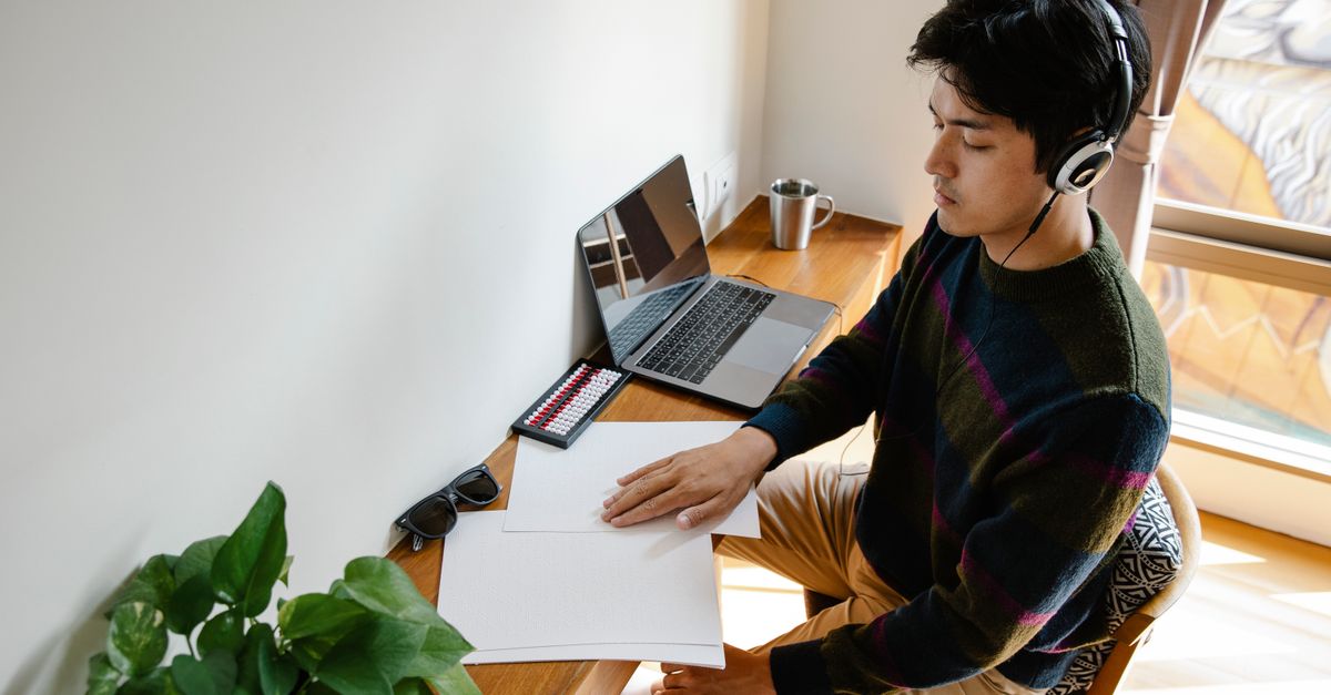 Homem adulto concentrado, trabalhando em uma mesa com laptop
